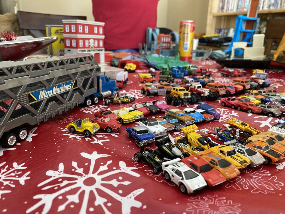A tabletop covered in vintage Micro Machines cars with the semi-truck hauler and fire department playset